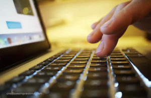 Mão tocando no teclado do laptop, usar internet